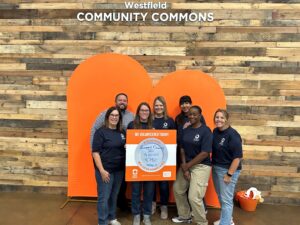 Group of people gathered together smiling and holding up Akron-Canton Regional Foodbank sign.