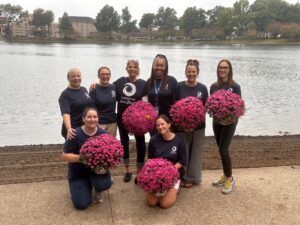 Group of people gathered together outside and smiling while holding flowers.