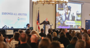 The keynote speaker on stage in front of hundreds of Summit DD team members.