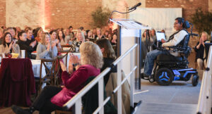 The keynote speaker on stage in front of hundreds of Summit DD team members.