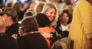 Superintendent Lisa Kamlowsky hugging a Summit DD team member in the audience.