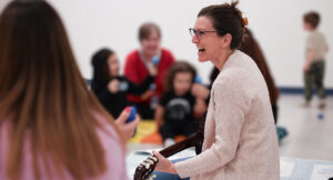 Music therapist performing to group of children.