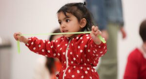 Young child playing with a green stretchy toy