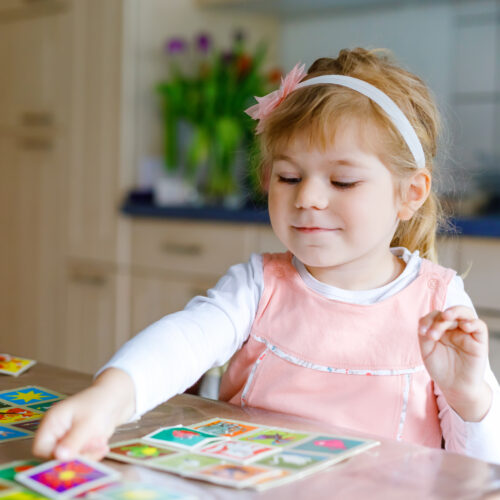 Toddler girl looking at picture cards on a table