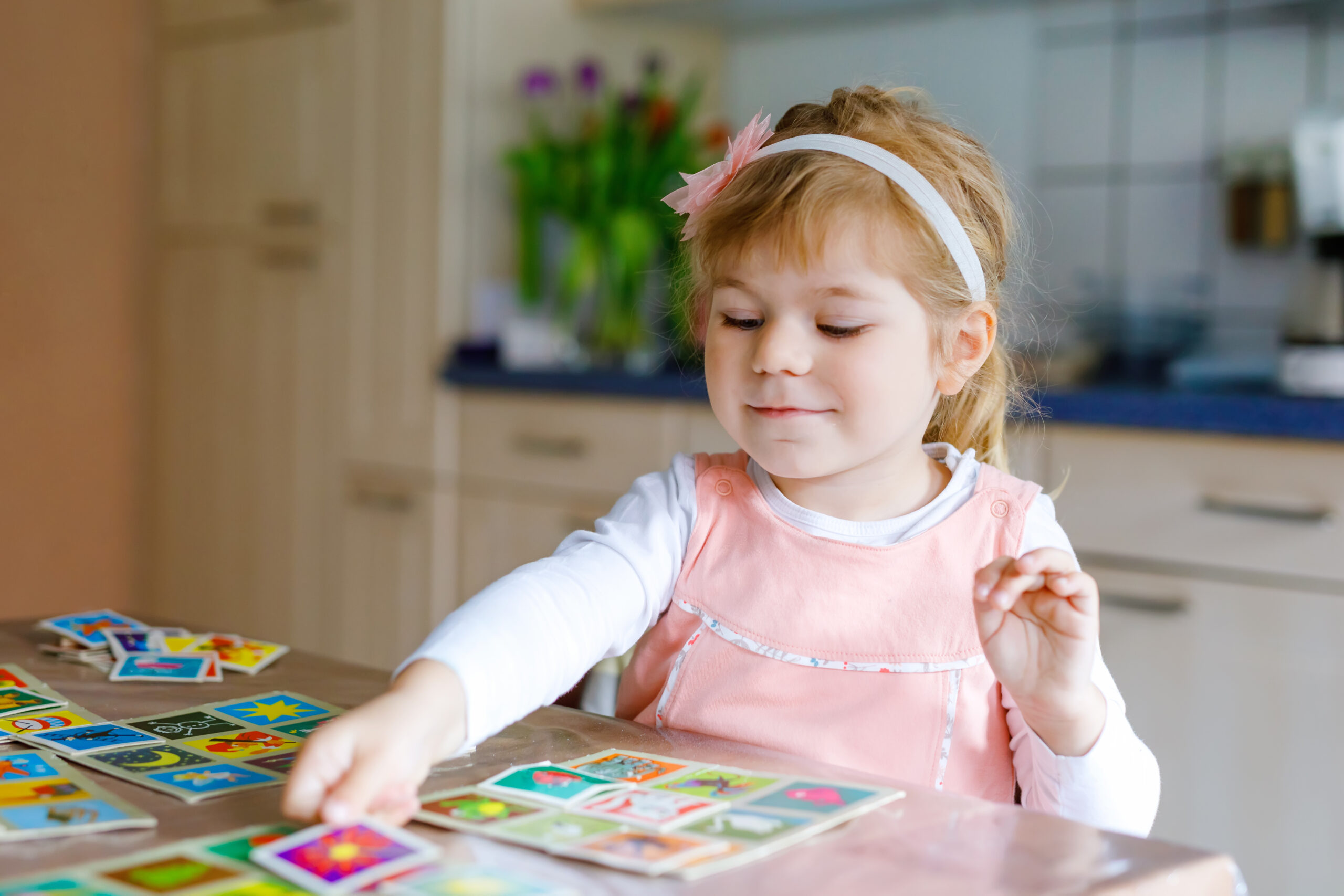 Toddler girl looking at picture cards on a table