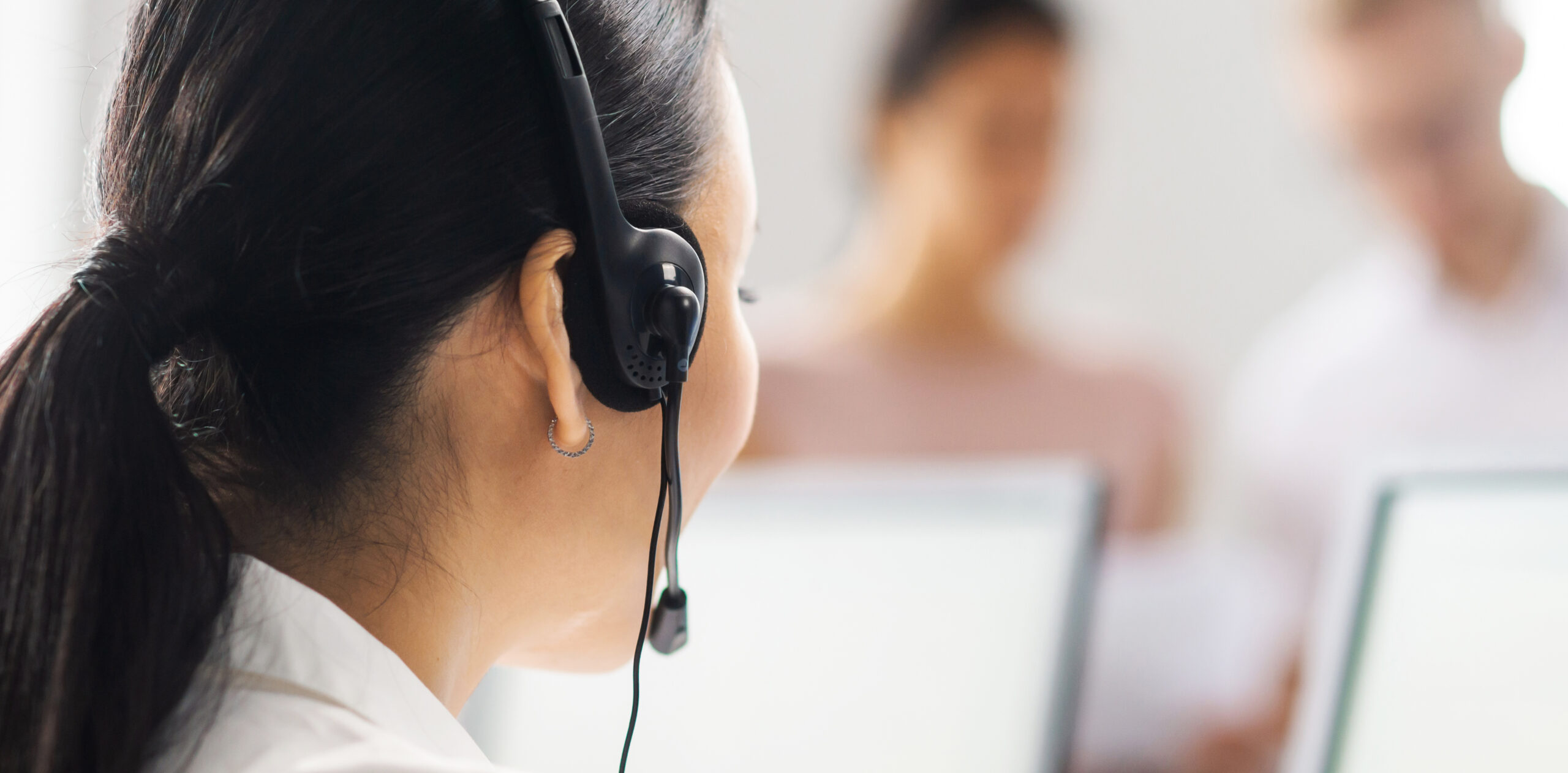 Image of the back of a female customer service representative wearing a headset and talking on the phone