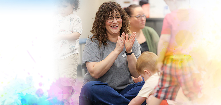Summit DD Speech Language Pathologist sitting on the floor smiling while engaging with kids in a playgroup.