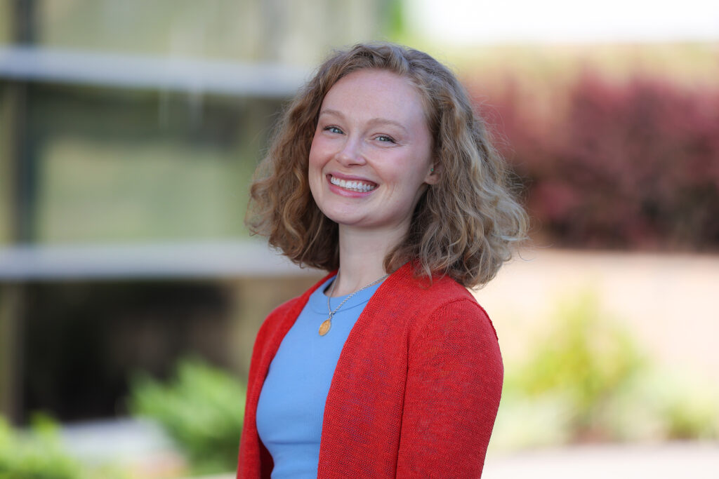 Portrait of new Summit DD staff member, Jenna Fisher, smiling in front of the Summit DD office building.
