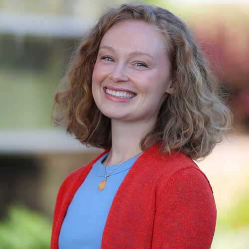 Portrait of new Summit DD staff member, Jenna Fisher, smiling in front of the Summit DD office building.