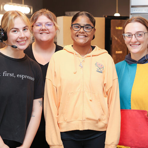 Smiling teen with a group of their coworkers at a local restaurant for the Summer Youth program.