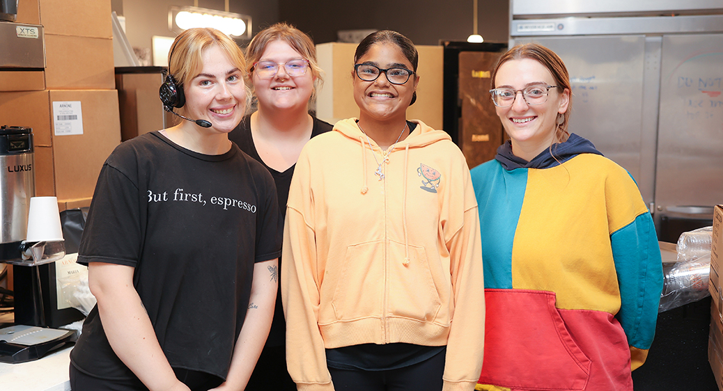 Smiling teen with a group of their coworkers at a local restaurant for the Summer Youth program.