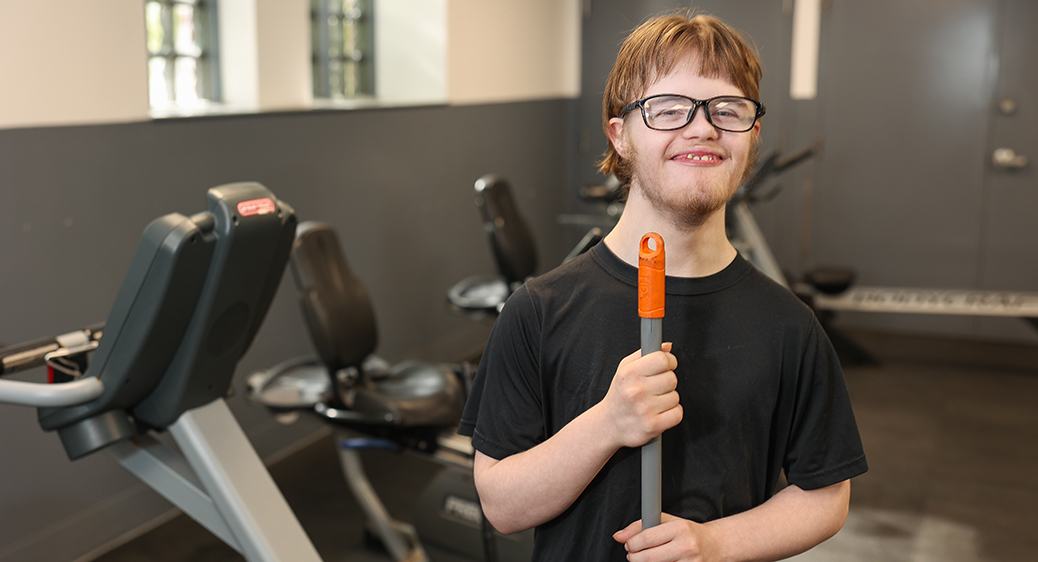 Smiling teen cleaning a local gym for the Summer Youth program.