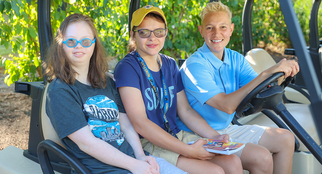 Smiling teens sitting in a golf cart with their job coach for the Summer Youth program.