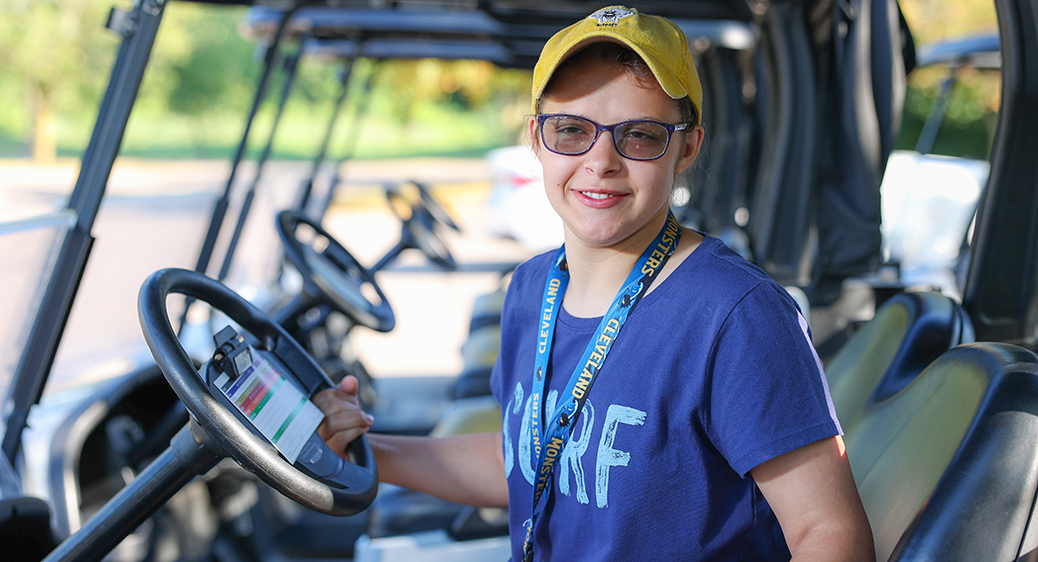 Smiling teen sitting in a golf cart for the Summer Youth program.