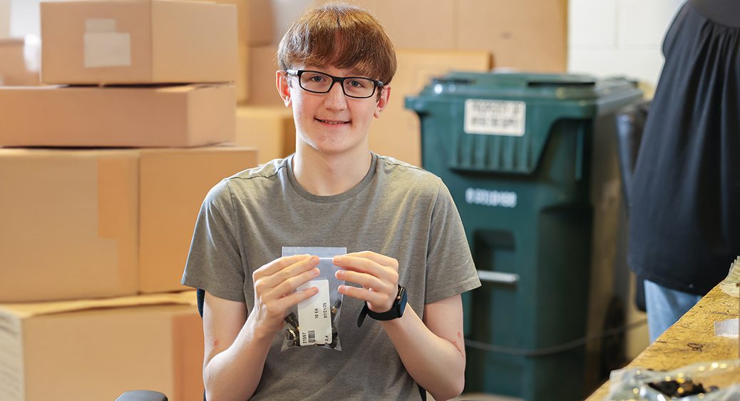 Smiling teen packing at a warehouse for the Summer Youth program.