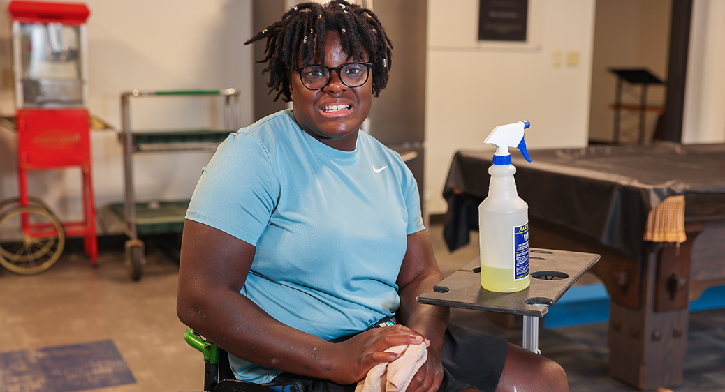 Smiling teen cleaning tables for the Summer Youth program.