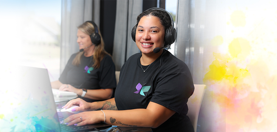 Female direct support professional smiling as she uses a laptop for remote monitoring supports.