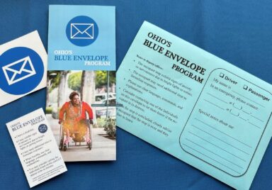 Blue Envelope Packet items laying on blue background: Blue envelope, brochure, decal and wallet card