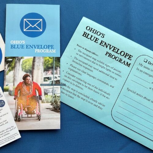 Blue Envelope Packet items laying on blue background: Blue envelope, brochure, decal and wallet card