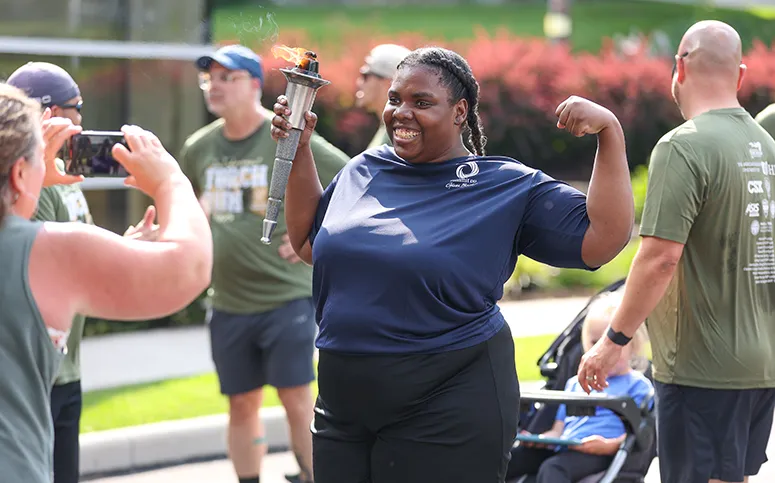 Special Olympian posing for a photo with the the Olympic flame, after she completed her leg of the Special Olympics Torch Run.