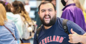 Grinning man wearing cleveland shirt, backpack, and earbuds
