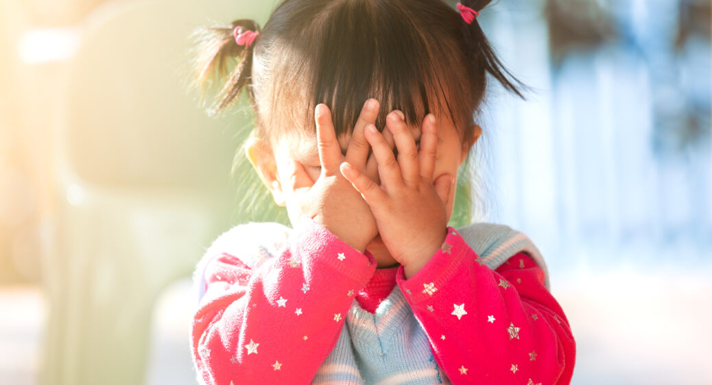 close up of toddler with 2 little pigtails playing peek-a-boo