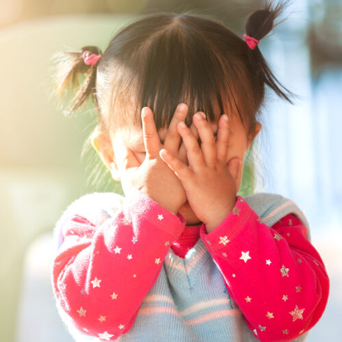 close up of toddler with 2 little pigtails playing peek-a-boo