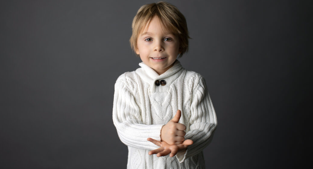 Smiling toddler demonstrating the ASL sign for "help"