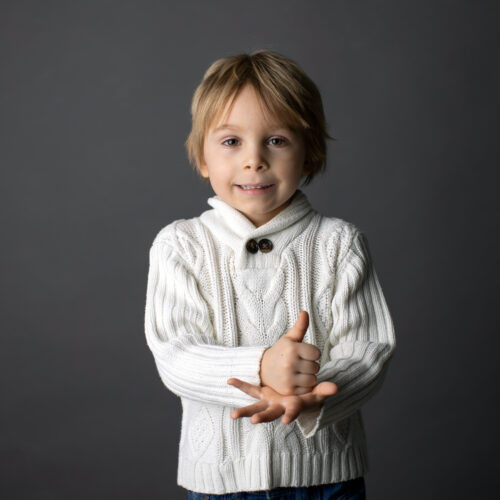 Smiling toddler demonstrating the ASL sign for "help"