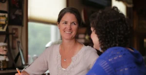 Image of smiling S.S.A. meeting with young woman in blue (whose back is to the camera)