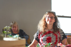 Proud artist sitting at a table with her artwork