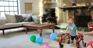 Child using a walker in their living room with the assistance of their Summit DD Developmental Specialist.