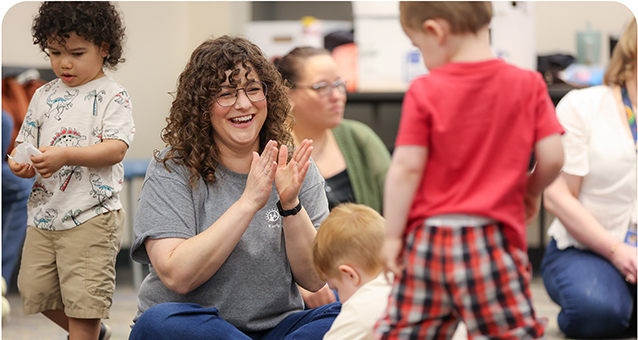 Smiling Early Intervention Speech Language Pathologist, Abigail Cureton, playing with children on the floor.