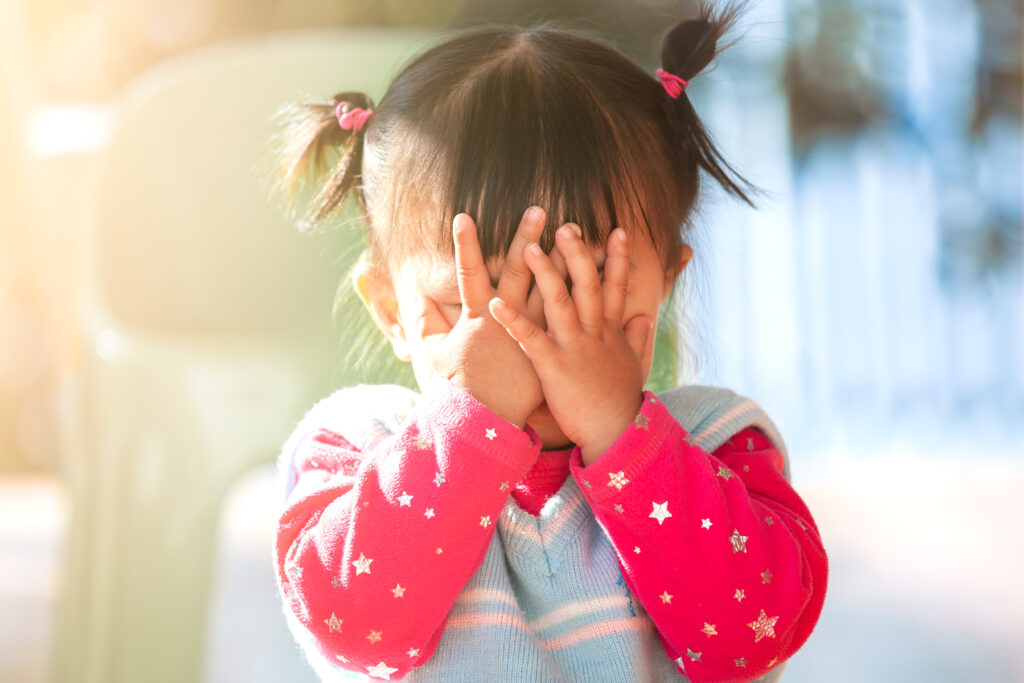 Toddler playing peekaboo and covering her face with her hands