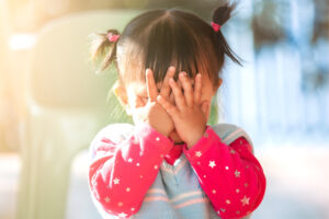 Toddler playing peekaboo and covering her face with her hands