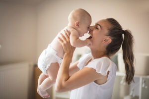 mom lifting up infant in diapers in playful manner