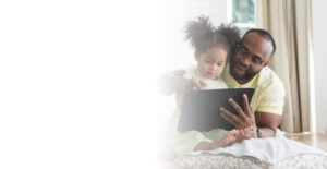 Father and baby daughter sitting together using digital tablet to learn or communicate