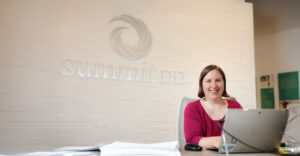 Smiling portrait of front desk receptionist, Mary Helen, sitting in the lobby at our Cuyahoga Falls office.