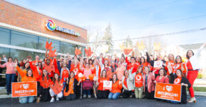 Large group photo of nearly 100 cheering Summit DD team members in front of the Summit DD building in downtown Cuyahoga Falls.