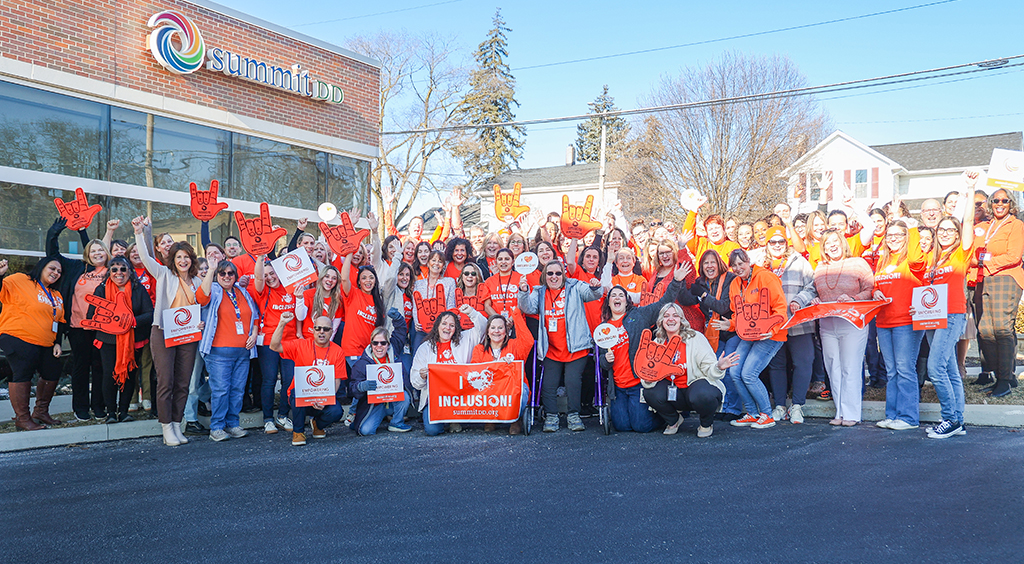 Large group photo of nearly 100 cheering Summit DD team members in front of the Summit DD building in downtown Cuyahoga Falls.