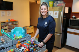 Smiling volunteer sorting a bin of toys