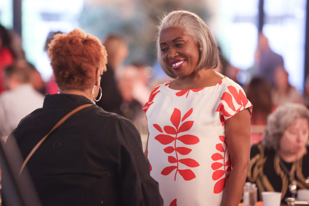 Summit DD Board member, Allyson V. James smiling and talking with another guest at the Summit DD breakfast