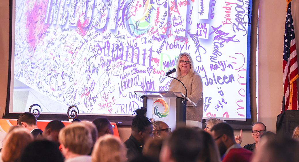 Superintendent Lisa Kamlowsky behind a podium speaking in front of hundreds of people at the Summit DD Community Breakfast.