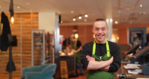 Smiling portrait of a young man with Down syndrome working at Panera.