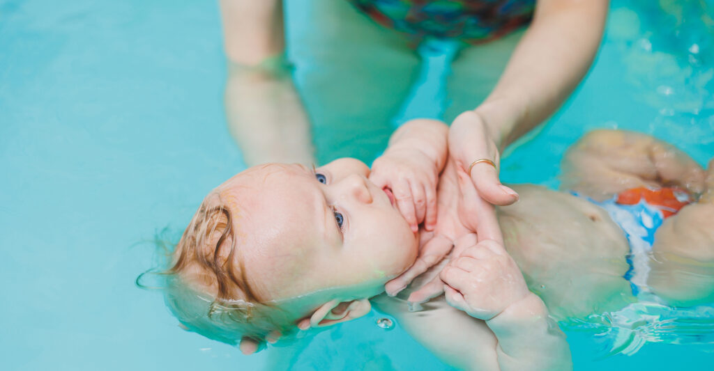 decorative image of baby in a pool with an instructor gently holding the baby's head