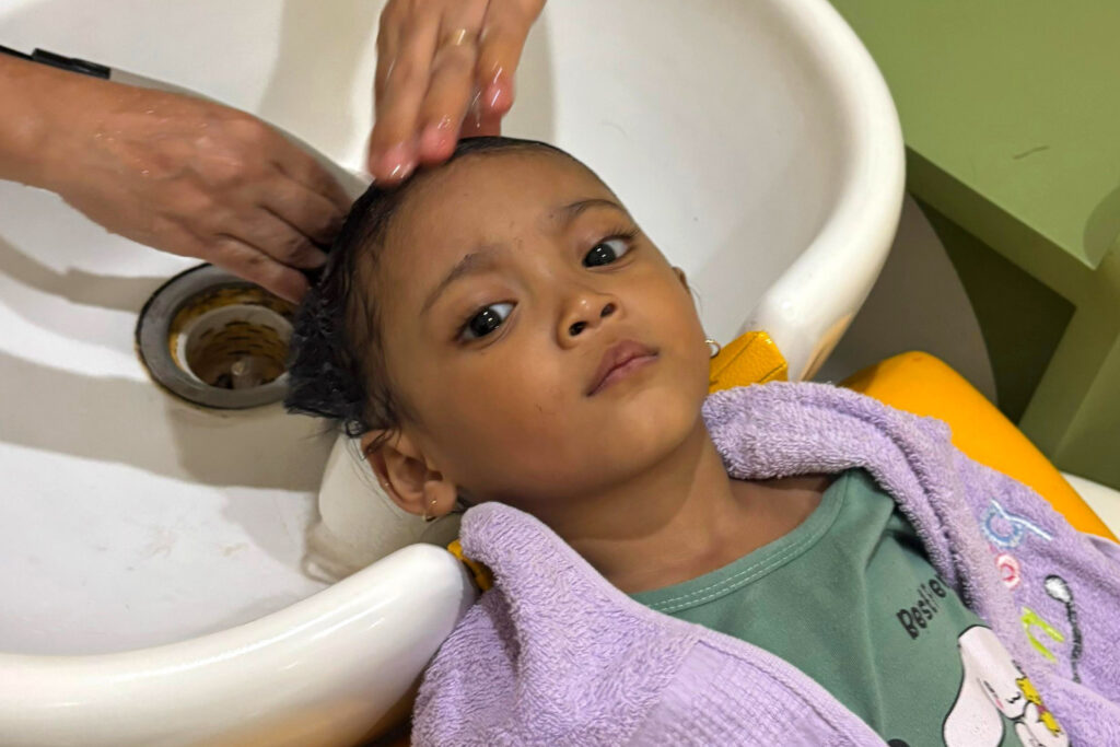 Image from above of a little girl getting a hair washed at a kids barbershop
