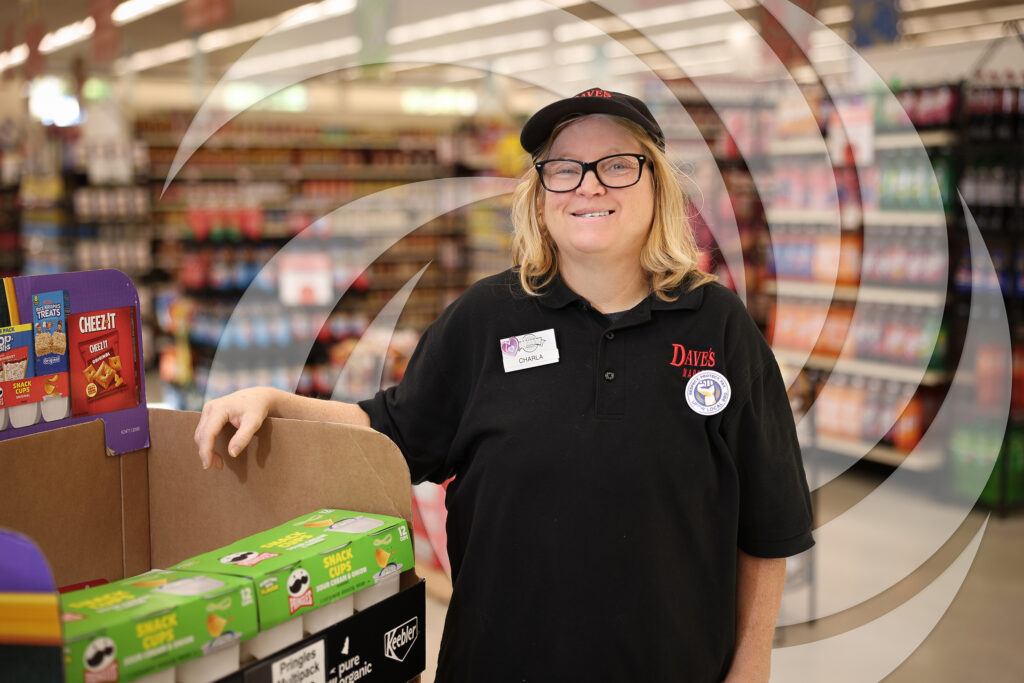 Smiling woman standing in a grocery store where she is employed.