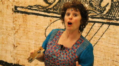 Noa Baum holds a tambourine mid-speech.
