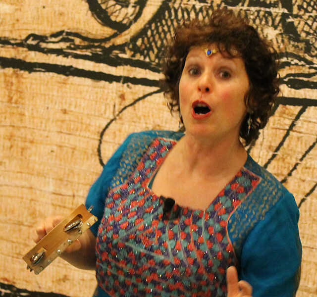 Noa Baum holds a tambourine mid-speech.