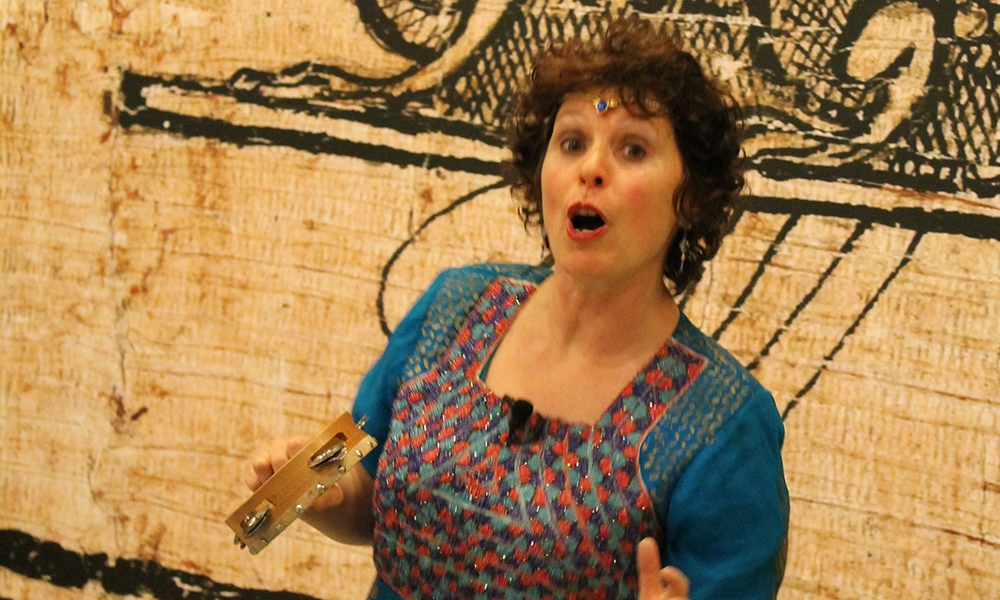Noa Baum holds a tambourine mid-speech.